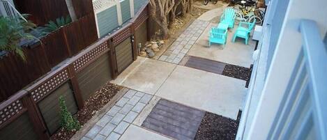Un patio trasero con zona de patio, mobiliario exterior, un cerco de madera y un árbol.