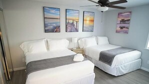 A hotel room with two beds, a ceiling fan, and artwork on the walls.