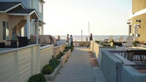 A pathway leading to a beach area with outdoor seating and a view of the ocean.
