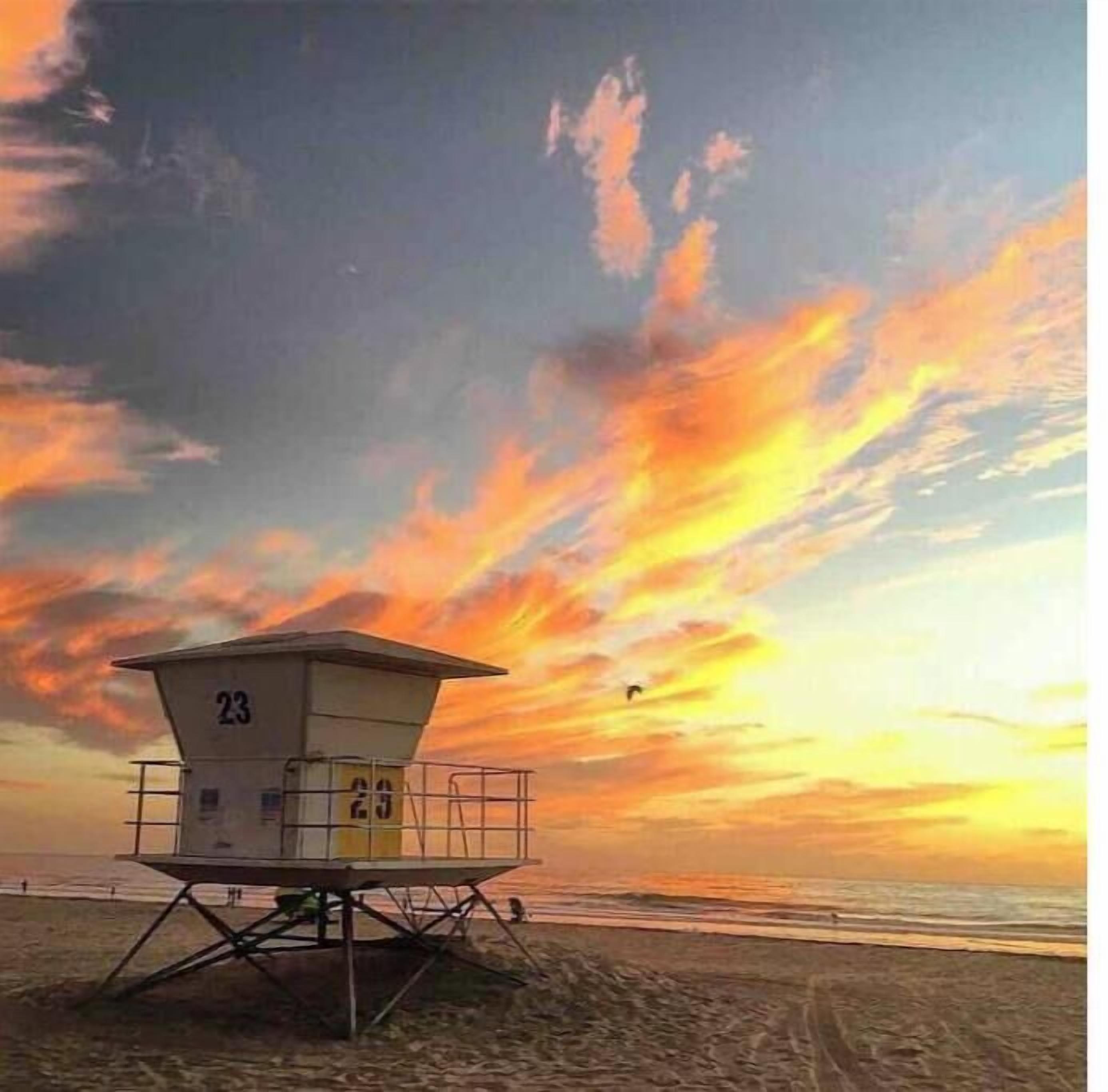 A lifeguard tower with the number 23 on a beach during sunset.