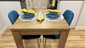 A wooden dining table with two blue chairs, each with a yellow napkin tied with a string. - The Prairie Nest (Saskatoon)