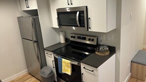 A compact kitchen with a refrigerator, microwave, stove, and oven. - The Prairie Nest (Saskatoon)