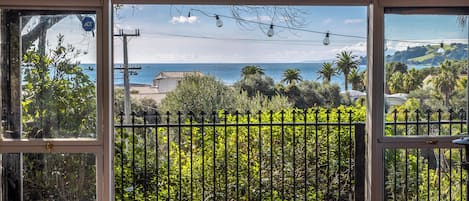 A balcony with a view of the sea, a wooden table, and a metal fence.