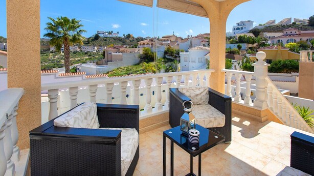 A balcony with wicker furniture, a small table, and a view of a residential area. - CH Villa Oceania La Marquesa Golf (Ciudad Quesada)