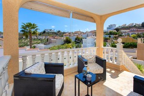Un balcon doté de meubles en osier, d’une petite table et offrant une vue sur un quartier résidentiel.
