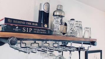 A bar shelf with a book titled 'Behind the Bar', a bottle of liquor, and several glasses.