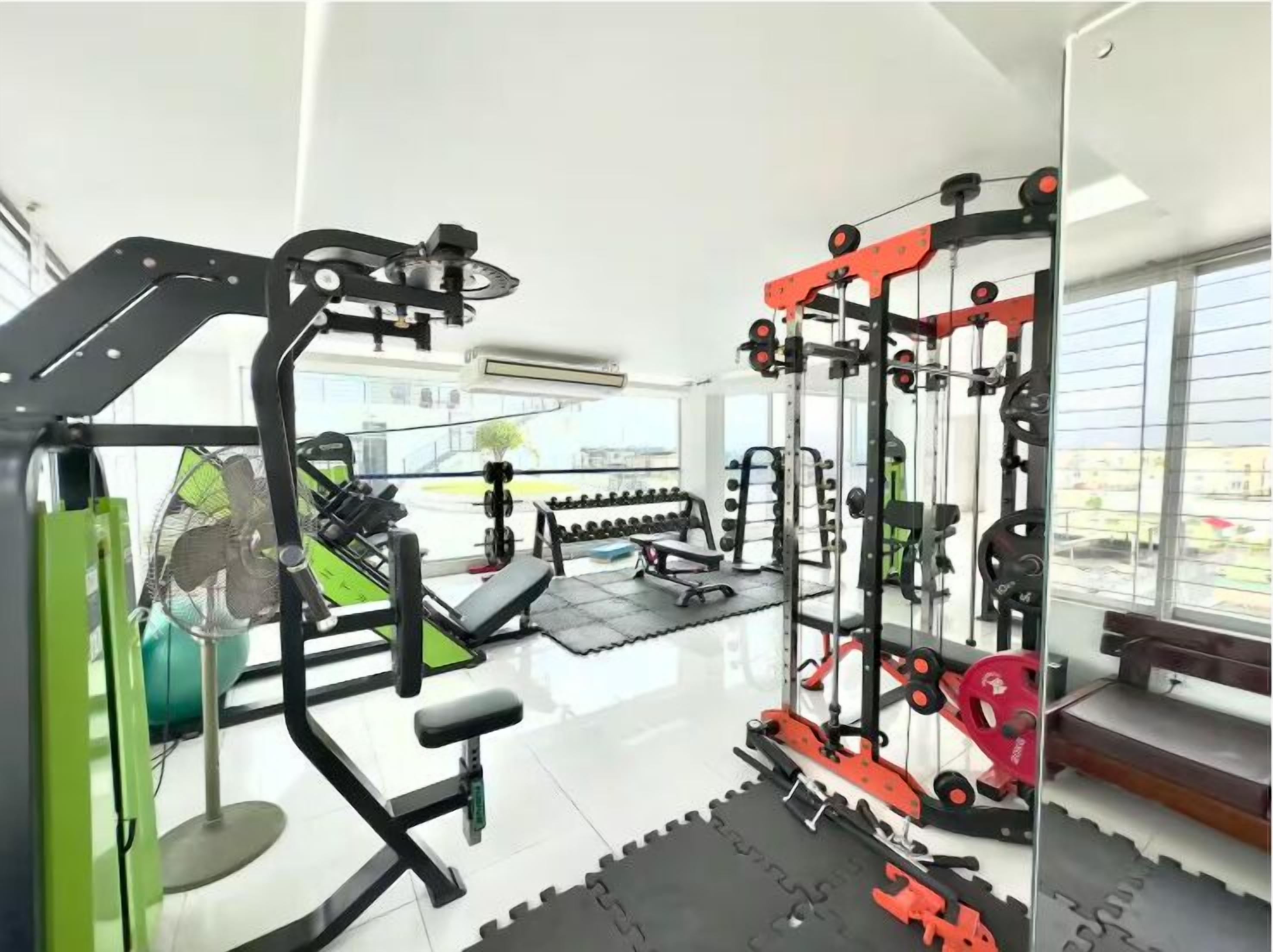 A gym with various exercise equipment, including a squat rack, bench press, and free weights.