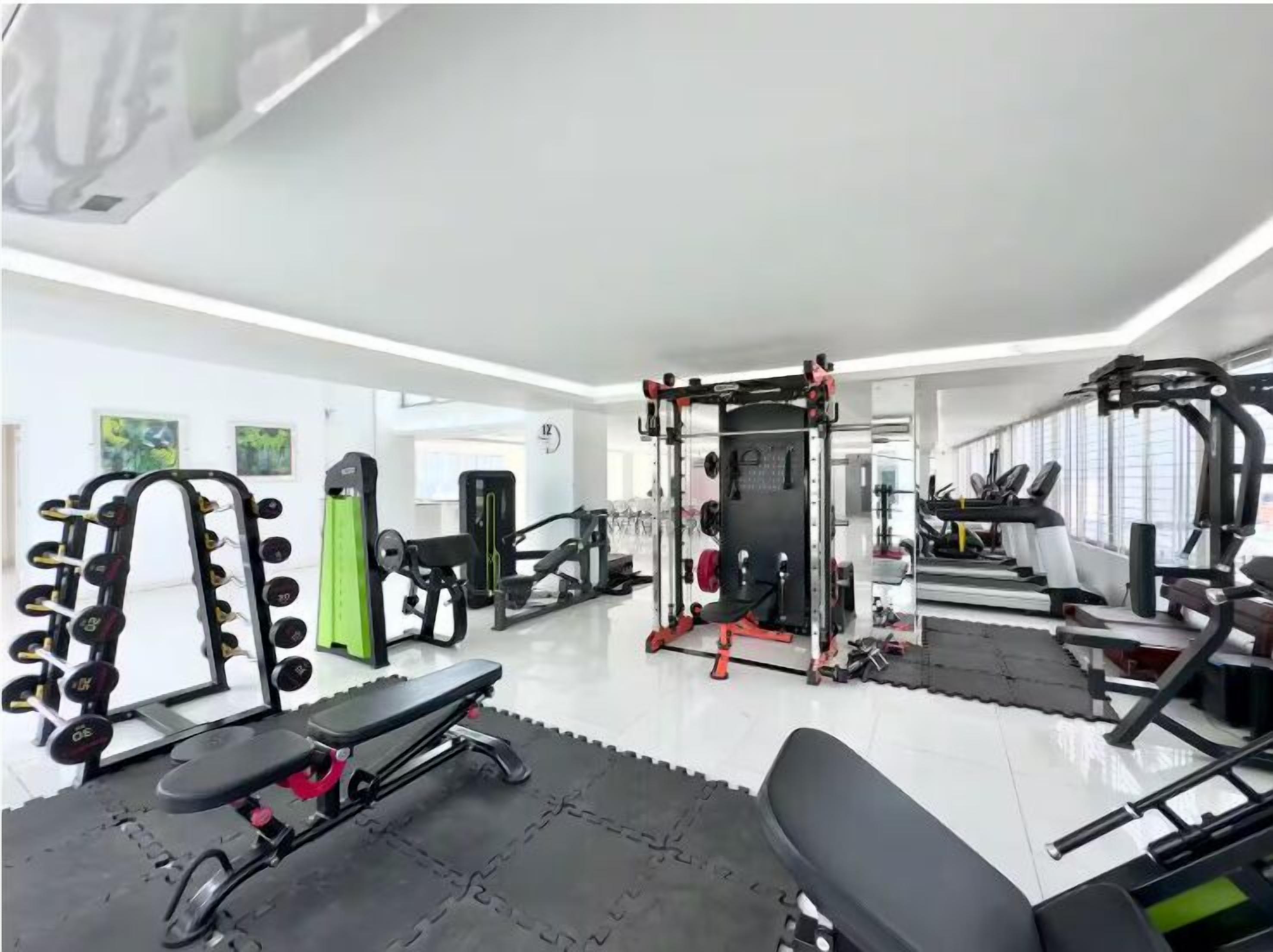 Une salle de sport moderne équipée de divers appareils d’exercice, notamment un support à squat, un banc de développé couché et des poids libres.