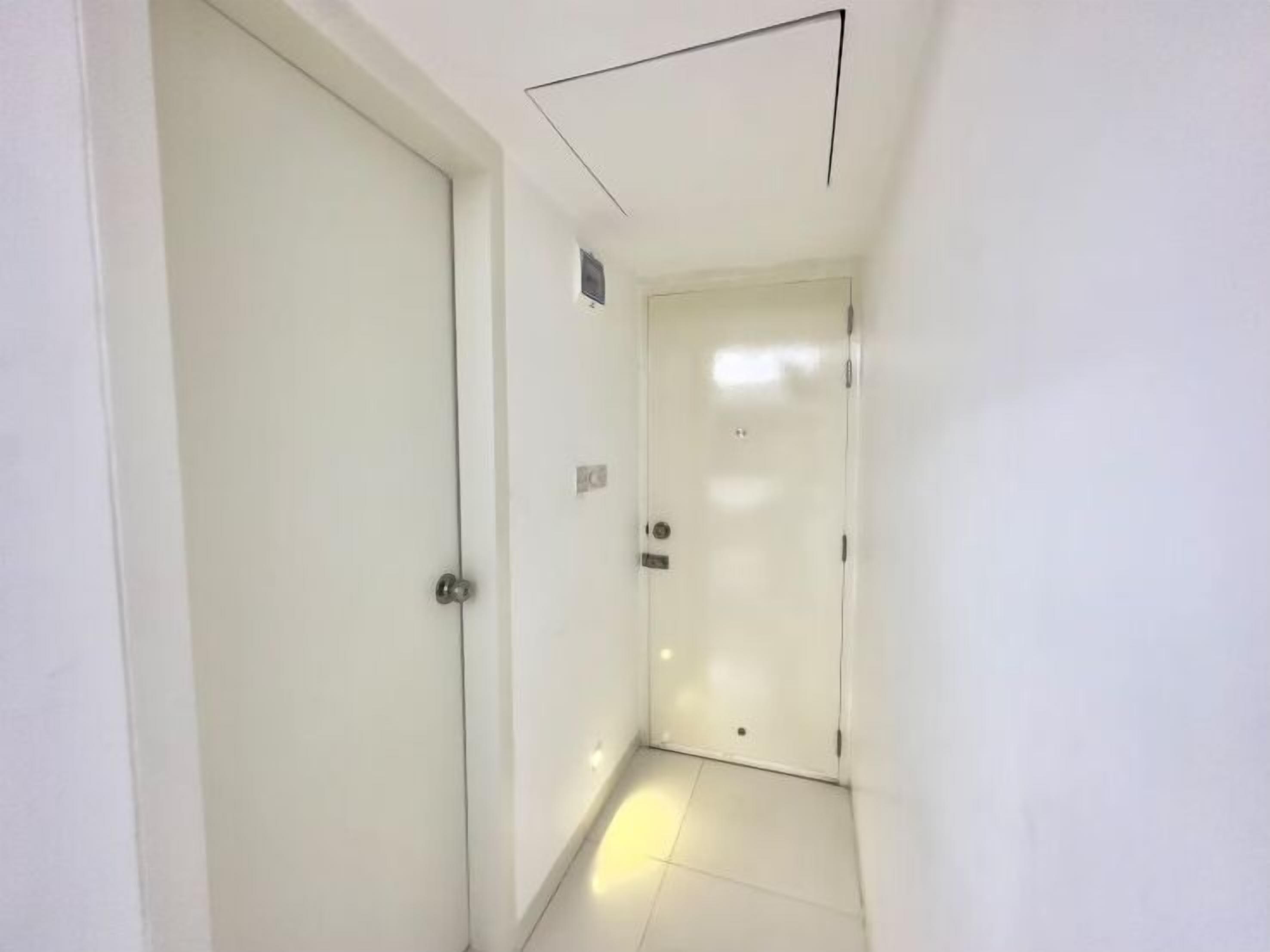 A narrow hallway with white walls and a tiled floor.
