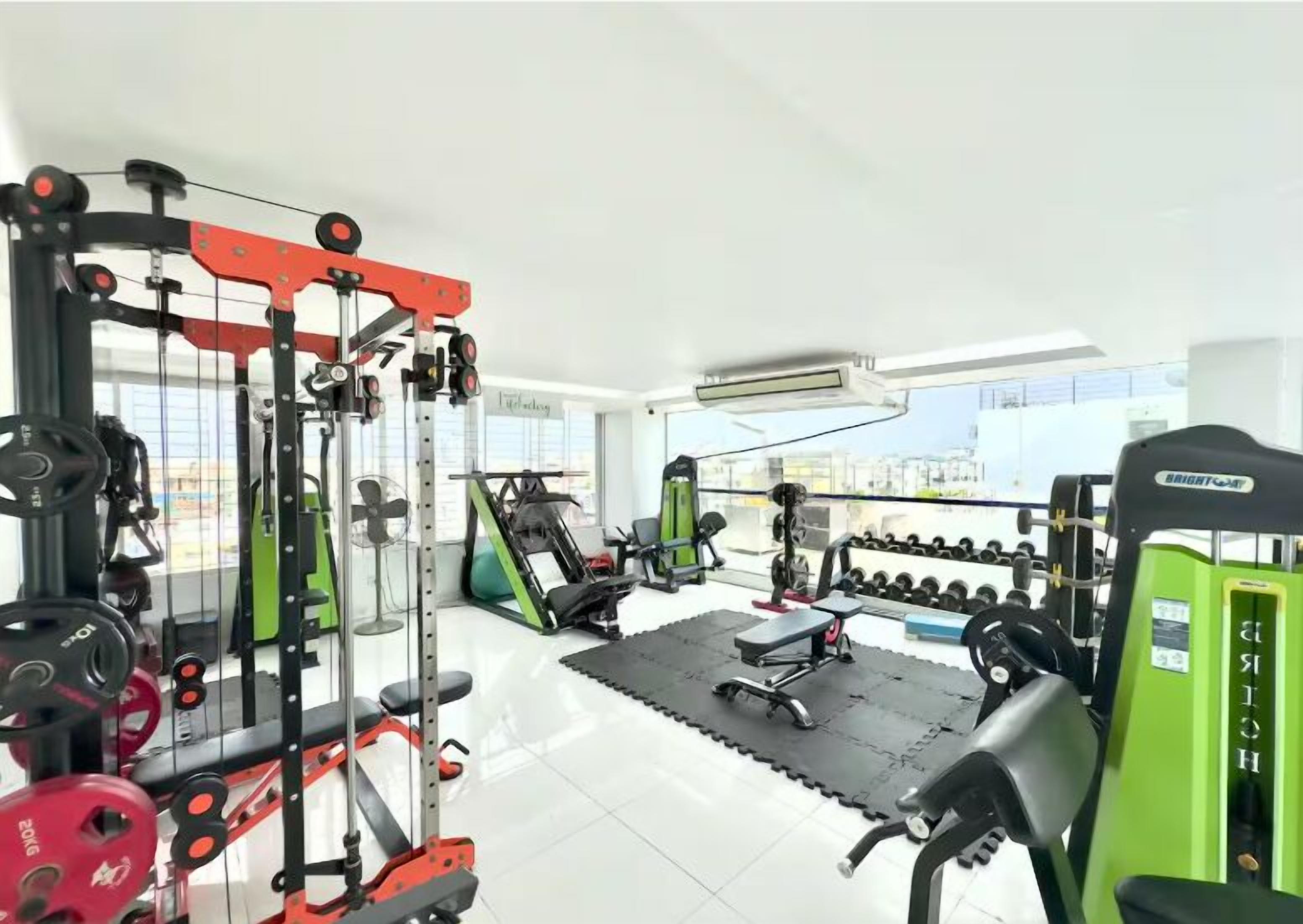 A gym with various exercise equipment, including weight machines, a bench, and dumbbells.