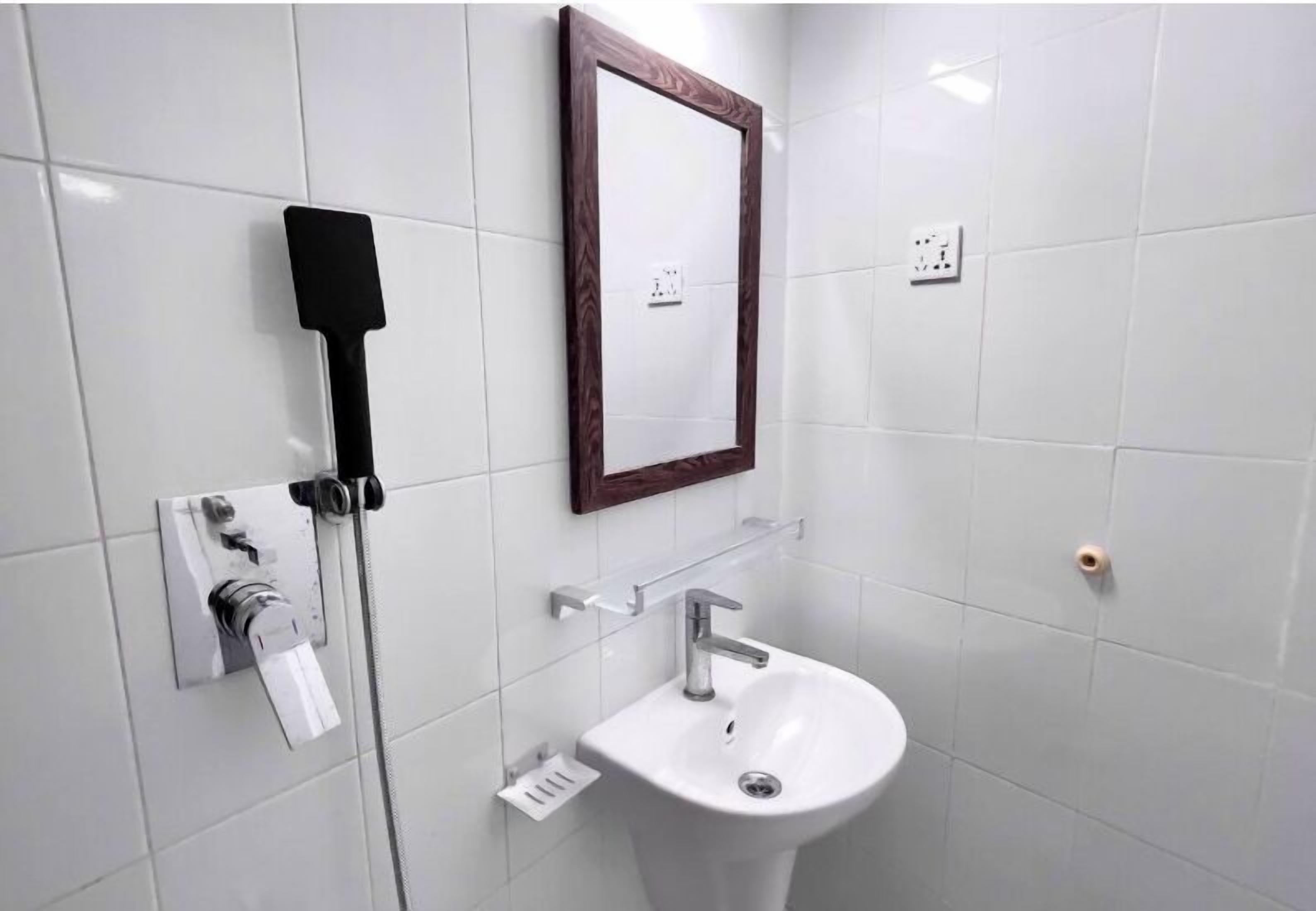 A bathroom with a white sink, a mirror, and a showerhead.