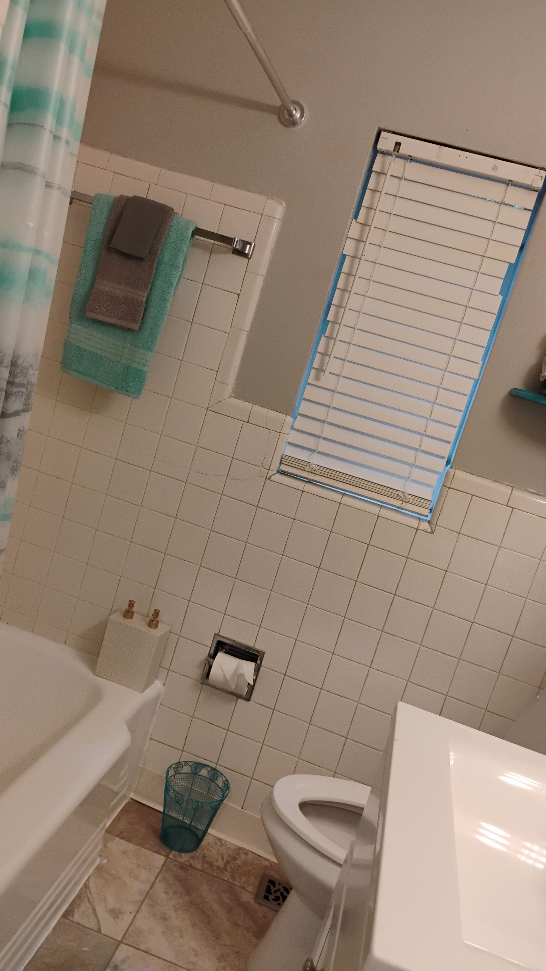 Een badkamer met een bad, toilet en wastafel. Er is een handdoekrek met handdoeken en een douchegordijn.