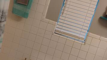 Een badkamer met een bad, toilet en wastafel. Er is een handdoekrek met handdoeken en een douchegordijn.