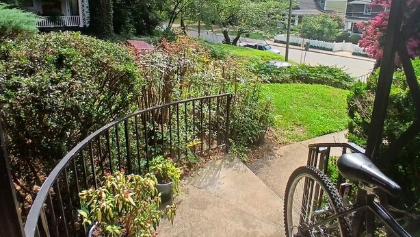 Ein Wohngebiet mit einem Fahrrad auf einem Betonweg, umgeben von Grünflächen und Häusern.
