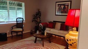 Ein Wohnzimmer mit einer Couch, einem Sessel, einem Couchtisch, einer Lampe und einem gerahmten Bild an der Wand.