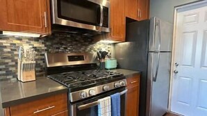 Una cocina con armarios de madera, estufa de acero inoxidable, microondas y refrigerador.