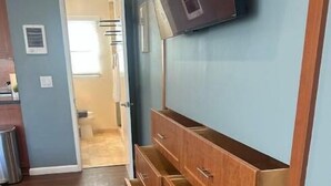 Una habitación con un armario de madera, un televisor de pantalla plana en la pared y suelo de madera.