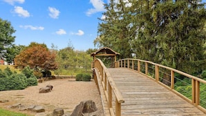 A wooden bridge leading to a gazebo in a landscaped garden with rocks and trees. - Franklin Park Gem - Historic meets Modern w/ Space for the Whole Crew - 4BR, 2BA (Columbus)