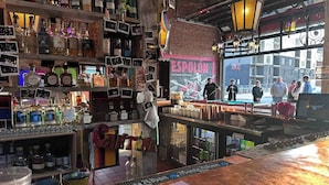 A bar with various liquor bottles, a menu, and a view of the street outside. - Franklin Park Gem - Historic meets Modern w/ Space for the Whole Crew - 4BR, 2BA (Columbus)