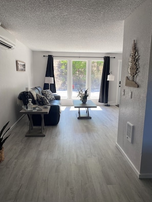 A modern living room with a sofa, a coffee table, and a view of a garden through large windows. - The Riverview Place - 2 bedroom house in Coulee Dam with WiFi, AC (Coulee Dam)