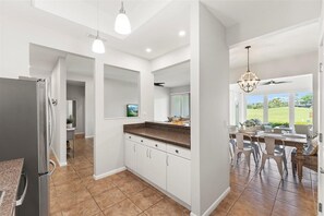 A modern kitchen with white cabinets, a granite countertop, and a dining area with a table and chairs.