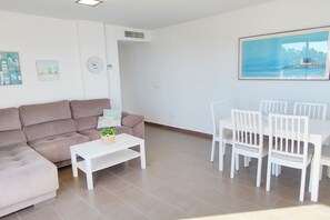 Un salon moderne comprenant un canapé, une table basse et un coin repas avec des chaises et une table.