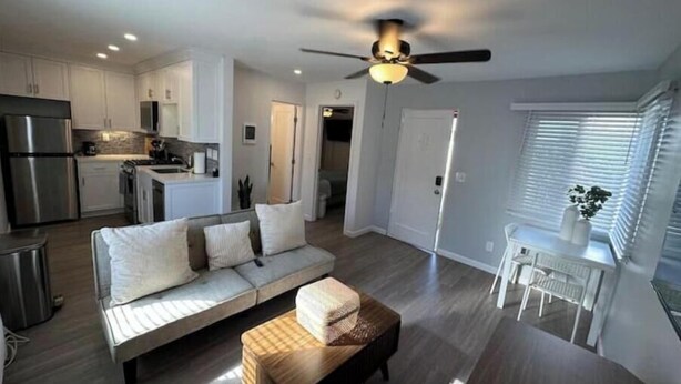 A modern living space with a sofa, ottoman, and a dining area with a table and chairs.