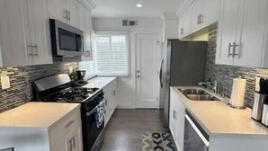 A modern kitchen with white cabinetry, a built-in microwave, a stove, and a refrigerator.