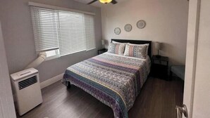 A bedroom with a bed, a ceiling fan, a window with blinds, and a heater.