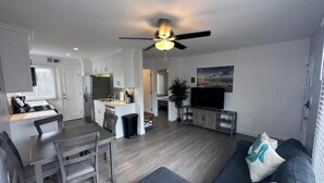 A modern living room with a sofa, TV, and ceiling fan.
