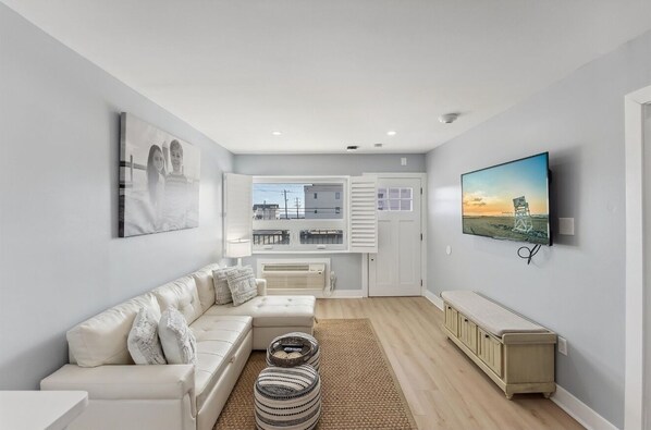 Relax in a spacious living room with a sofa, flat-screen TV, and large window offering a view of the outside.