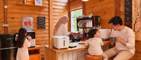 A cozy kitchen with wooden walls, a central island, and a refrigerator.