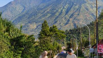 Una familia caminando por un camino pavimentado, con un paisaje montañoso al fondo.