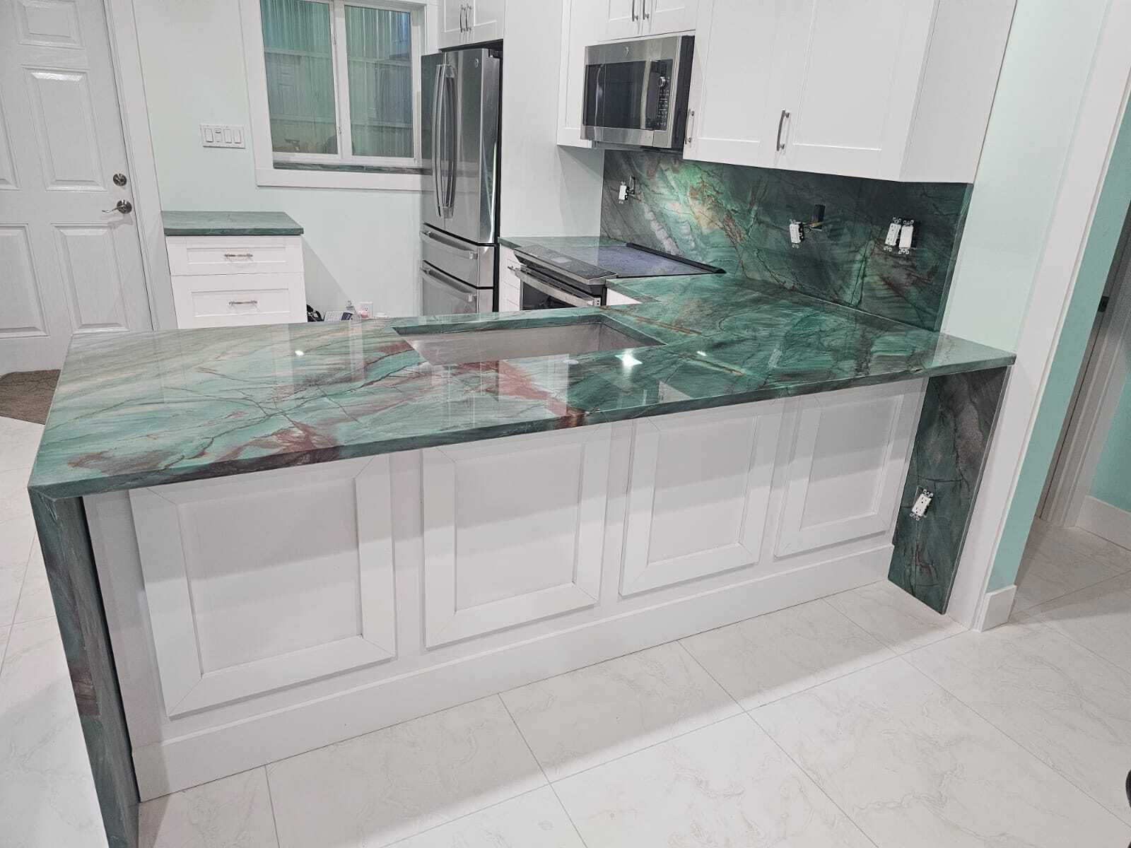 A kitchen with a marble countertop, white cabinetry, and stainless steel appliances.