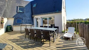Un patio con una mesa, sillas, una silla blanca y una cerca de madera.