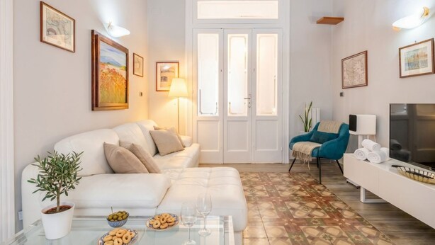 A living room with a sofa, a coffee table with snacks and glasses, a TV, and a door with glass panels.