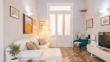 Ein Wohnzimmer mit einer Couch, einem Couchtisch mit Snacks und Gläsern, einem Fernseher und einer Tür mit Glasfeldern.