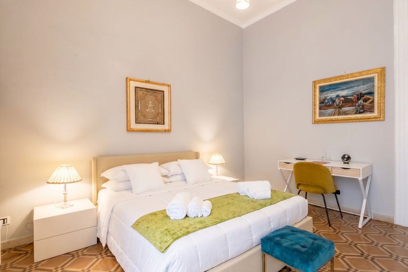 Une chambre d’hôtel avec un lit, des lampes de chevet, un bureau et une chaise.
