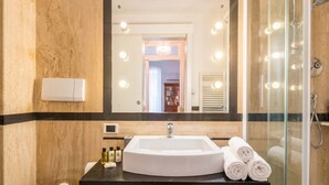 A bathroom with a large mirror, a sink, and a shower.