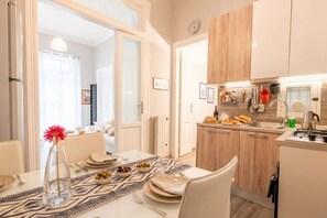 Una cocina moderna con armarios de madera, una zona de comedor con una mesa dispuesta para dos personas y vistas al salón contiguo.