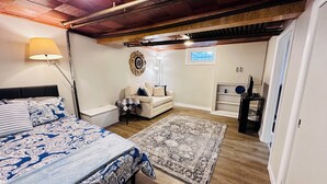 A bedroom with a bed, a sofa, a small table, a rug, and a TV stand. - Your Clean Clubhouse in St Boniface. Perfect for Students/Short term home away! (Winnipeg)