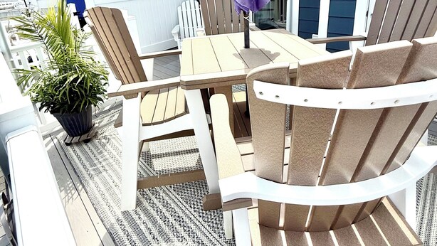 An outdoor deck with a wooden table and chairs, a purple umbrella, and a potted plant. - Charming Canal Water View Townhome with Outdoor Pool, WiFi & AC in Ocean City (Ocean City)
