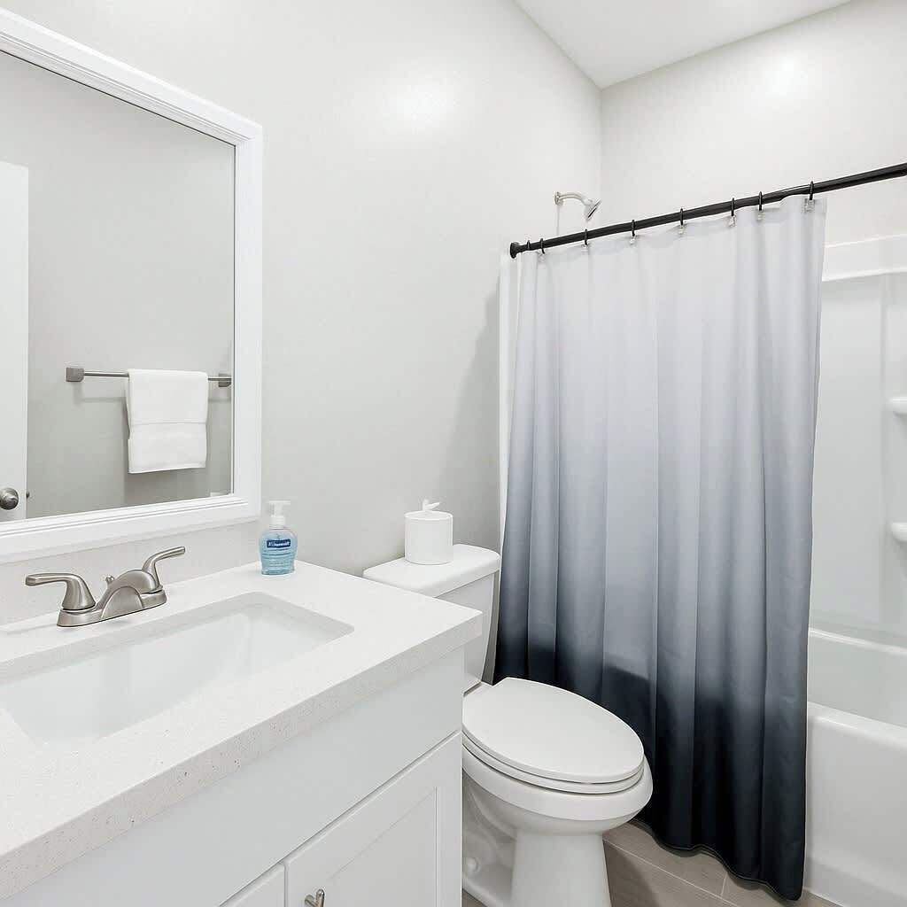 A bathroom with a white sink, a mirror, a toilet, and a shower curtain.