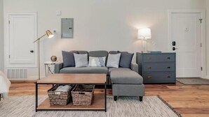 Un salon moderne avec un canapé gris, une table basse en bois et une commode bleue.