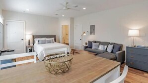 Une chambre à coucher moderne avec un lit, un canapé, une table à manger et un ventilateur de plafond.