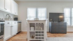 Une cuisine moderne avec des meubles blancs, un four à micro-ondes et un téléviseur.