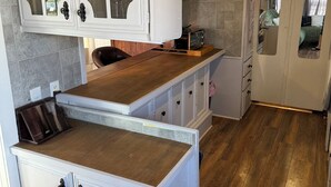 Une cuisine de taille réduite avec des meubles blancs, un plan de travail en bois et un revêtement mural en carreaux.