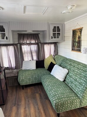 Une pièce chaleureuse avec un canapé à motifs verts, un banc en bois et une petite table.