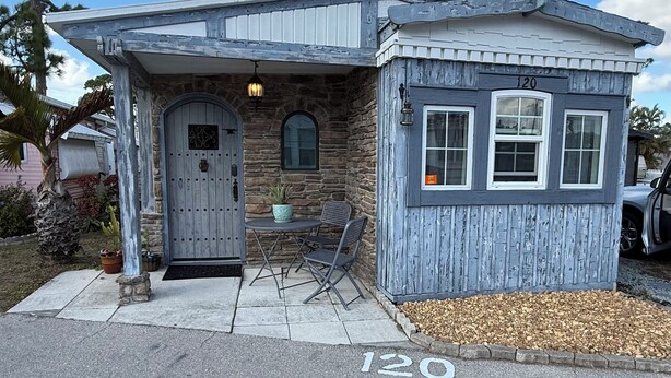 Une petite maison de plain-pied, avec une façade en pierre, une porte en bois et le numéro « 120 » affiché sur le devant.