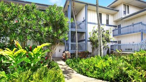 A hotel with a central courtyard, surrounded by lush greenery and palm trees. - 1st Floor 2BR Ocean View • Steps to Beach • Pool • AC • Sleeps 6 (Koloa)